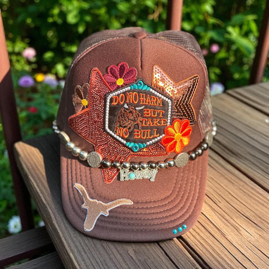 Brown “Do No Harm But Take No Bull” trucker hat with howdy hat chain, ornate teal rhinestones.